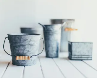 gray steel bucket on brown wooden bucket by Sixteen Miles Out courtesy of Unsplash.